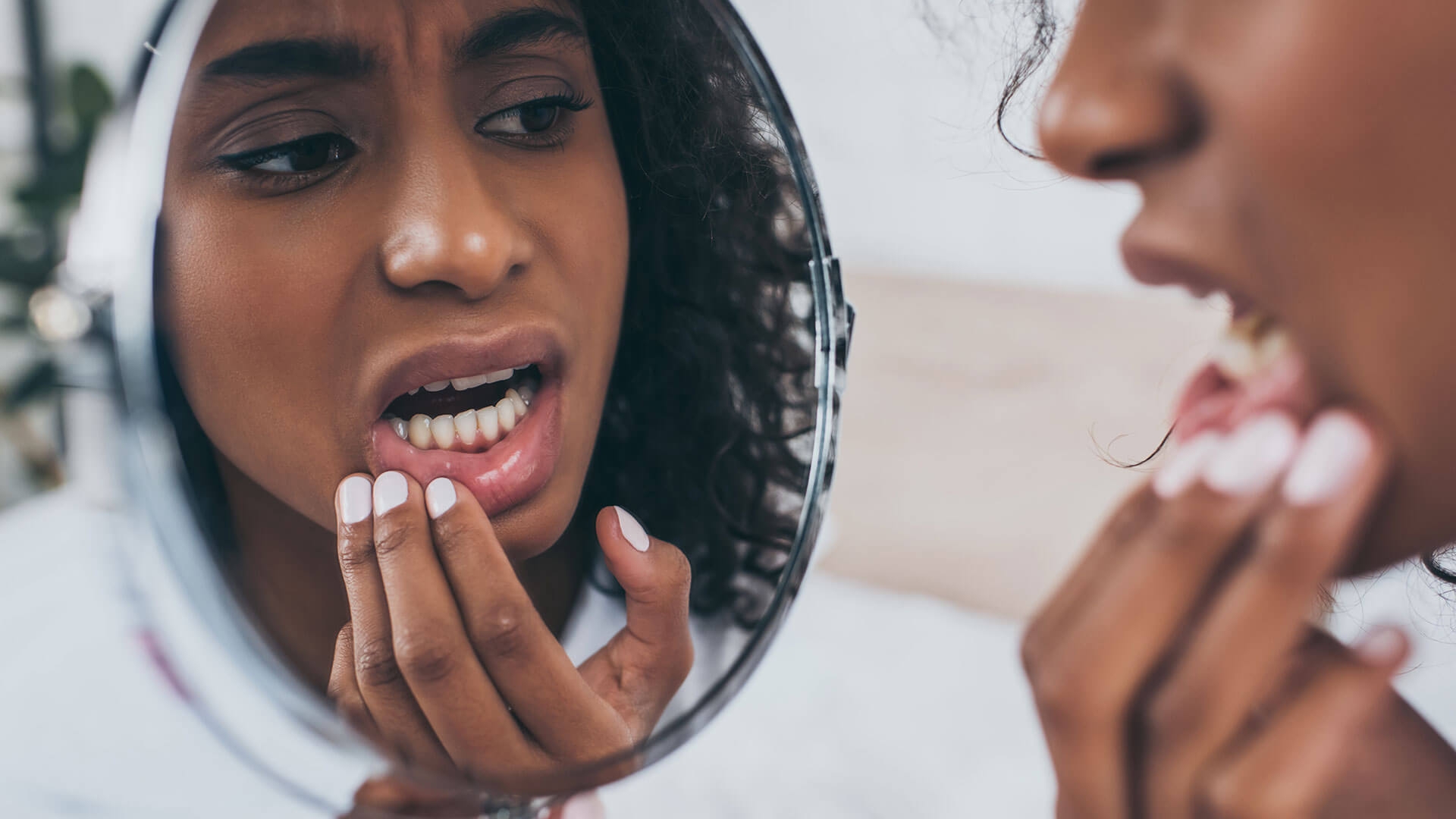 Woman checking her gum line in mirror looking for decay